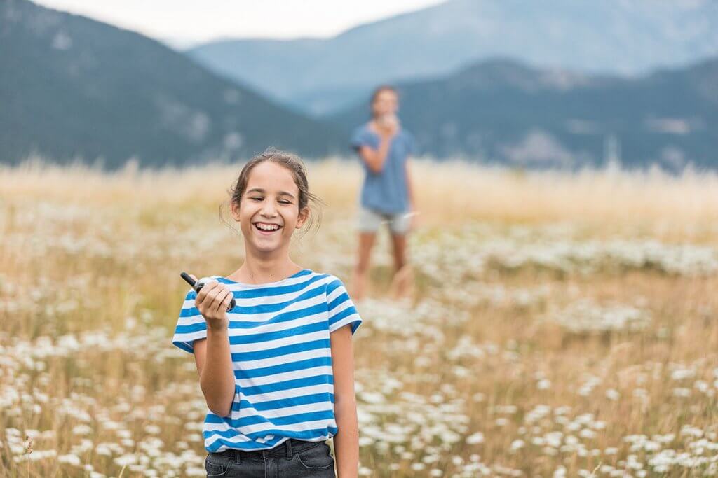 zwei Geschwister spielen mit Walkie-Talkies im Freien