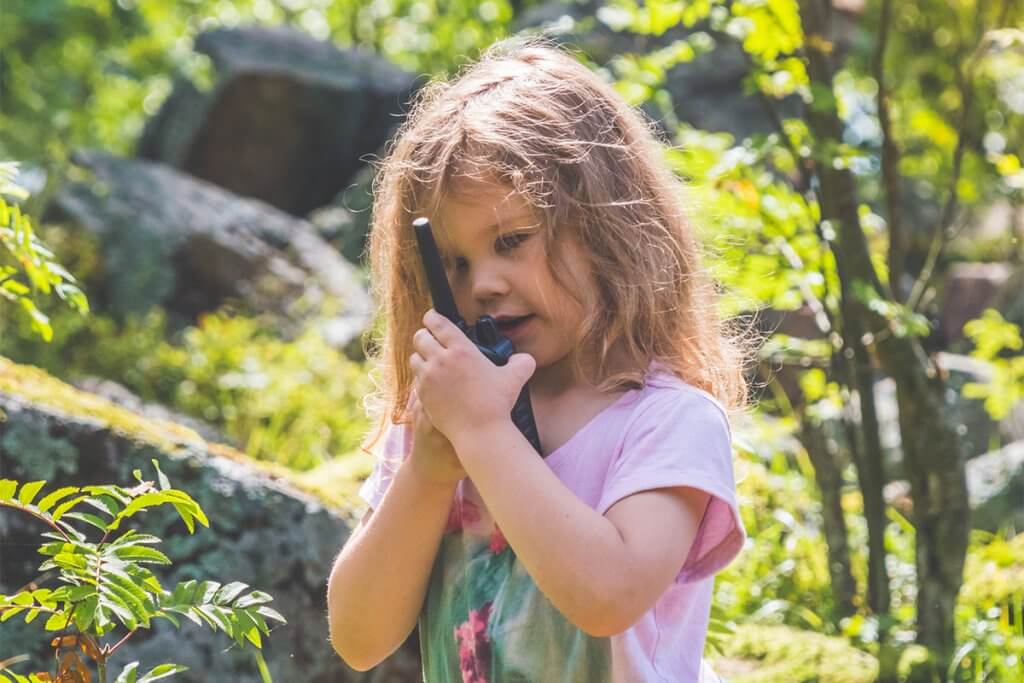 Kind spricht in ein Walkie-Talkie im Wald