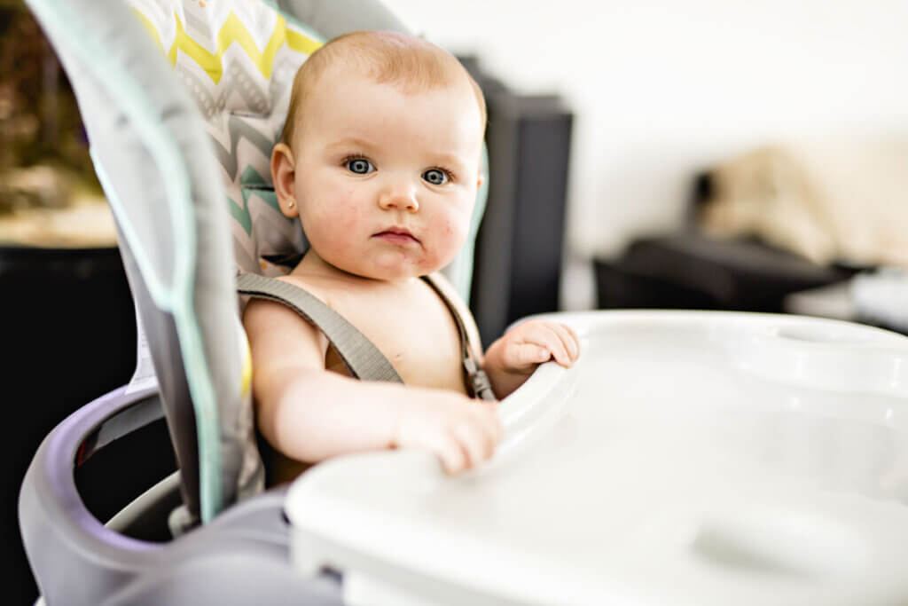 baby sitzt festgeschnalt in Hochstuhl