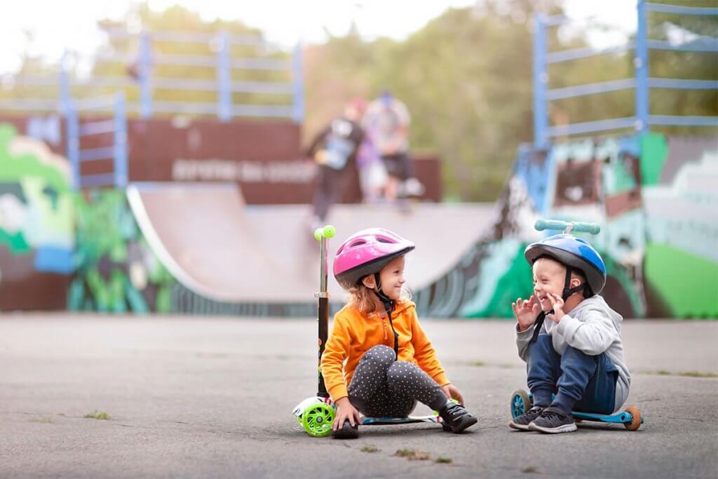 zwei Kinder mit Rollern