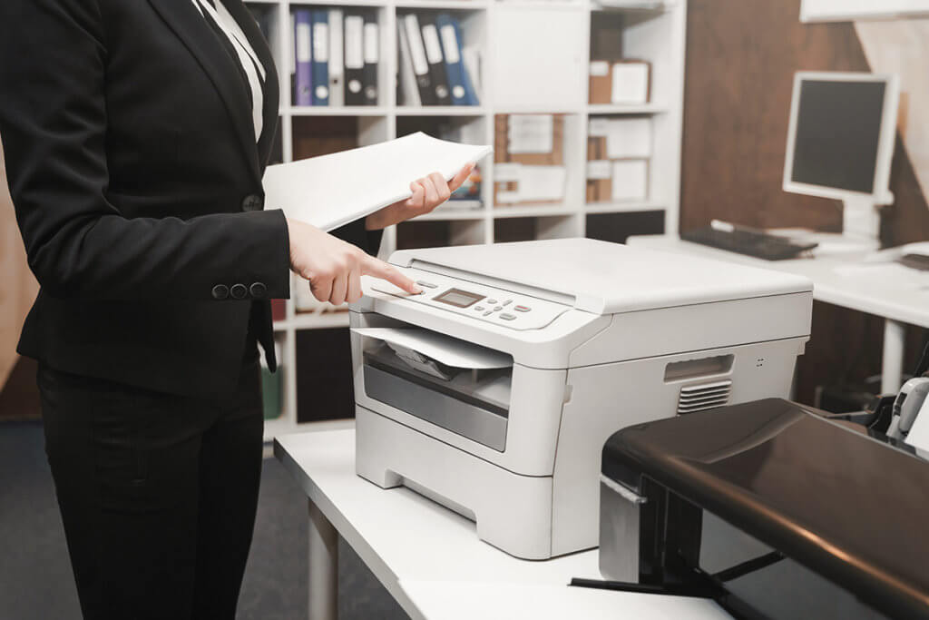 Frau in Blazer nutzt Multifunktionsdrucker in einem Buero