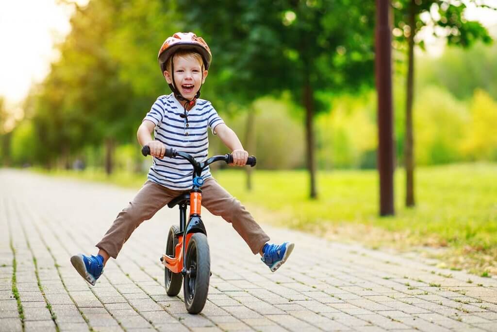 Kleiner Junge faehrt durch den Park