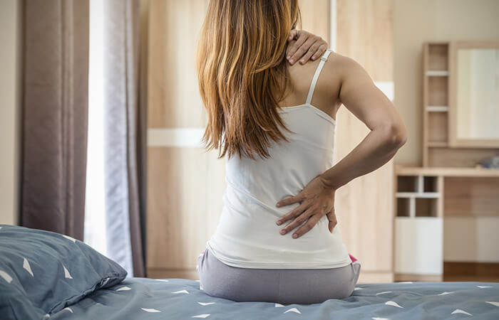 Frau mit Rückenschmerzen auf Bett