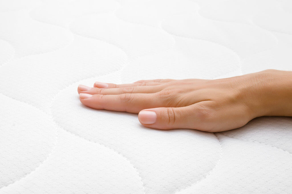 Matratzentopper Hand auf Matratze