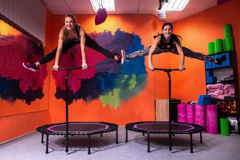 zwei Frauen springen auf Trampolin mit Haltegriff