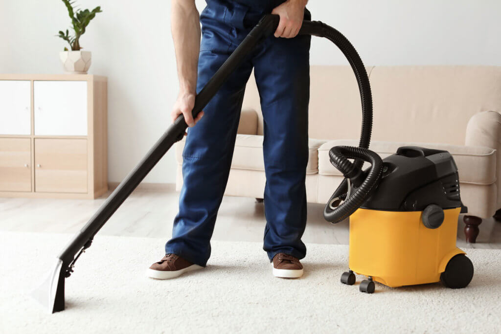 Mann saugt Teppich im Wohnzimmer