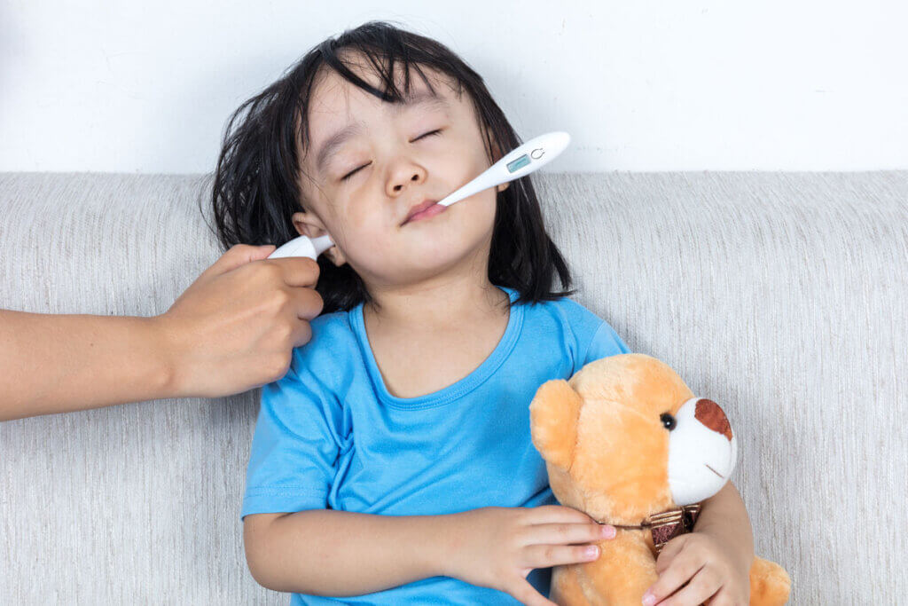 Kind mit Fieberthermometer in Ohr und Mund