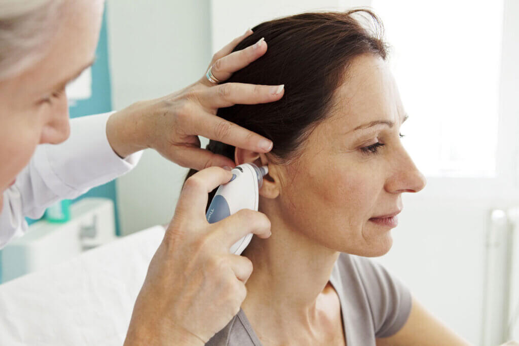 Arzt misst Fieber bei Frau im Ohr