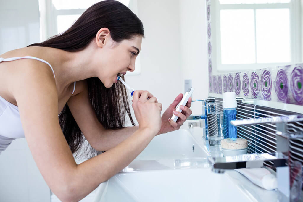 Frau nutzt Smartphone beim putzen