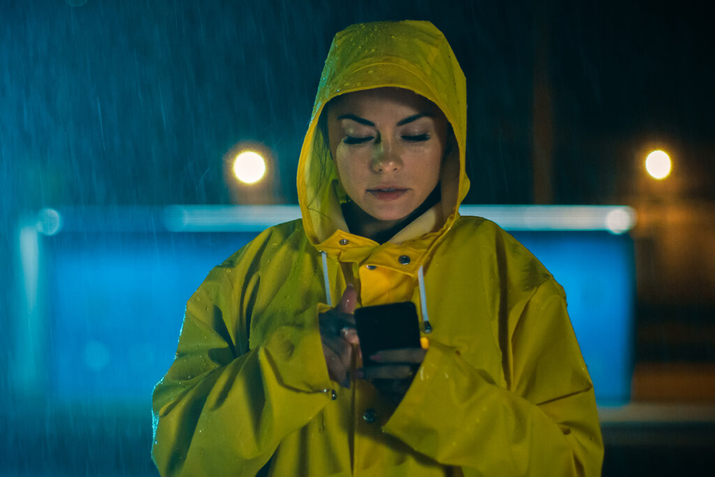 Frau im Regen nutzt Smartphone