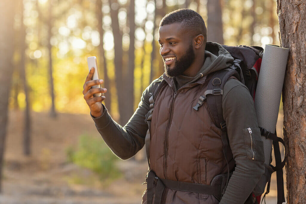 Mann im Wald schaut auf Smartphone