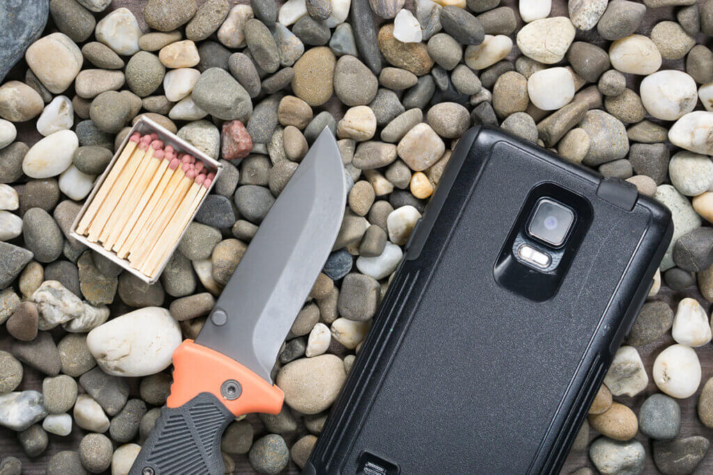 Messer Streichhölzer und Smartphone auf Kieselboden