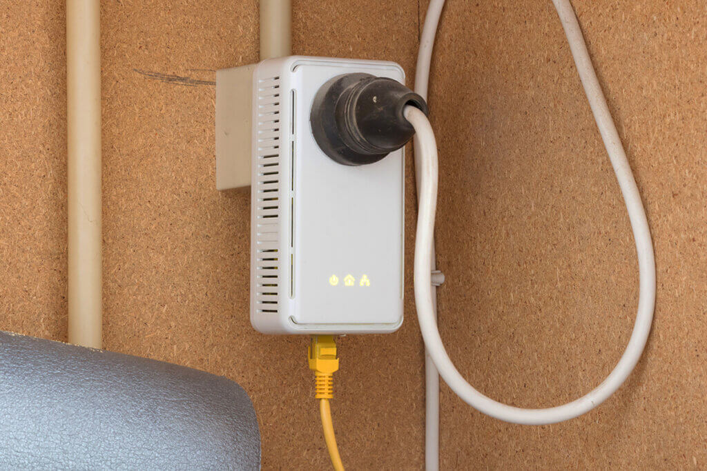 powerline-adapter steckt im schuppen in einer steckdose, die auf einer spanplatte installiert ist