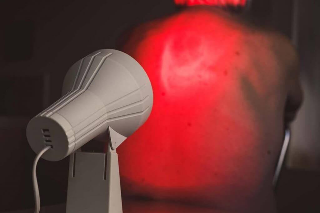 rotlichtlampe - rundlampe bestrahlt ruecken und nacken von mann