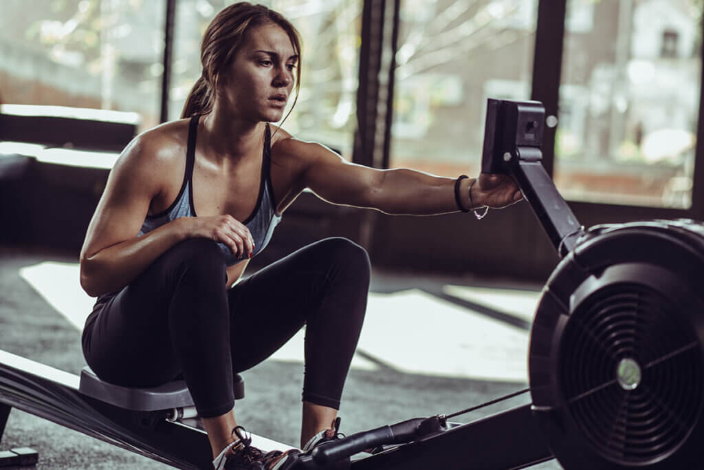 Frau im Fitnessstudio nutzt Rudergerät