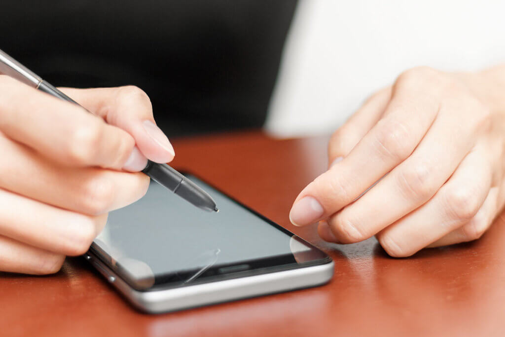 Frau bedient Smartphone mit Stift