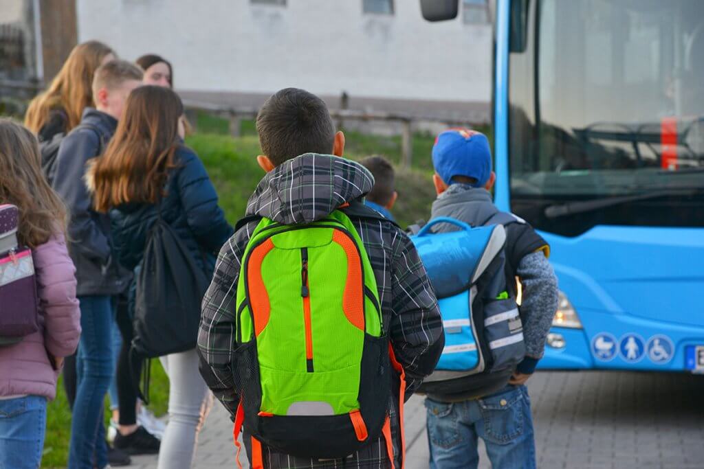 schueler mit neonrucksack auf dem weg zum schulbus