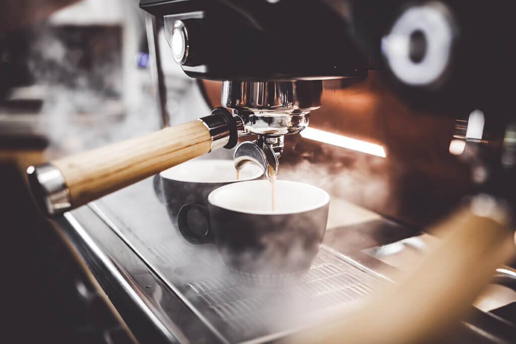 zwei Tassen werden mit Kaffee befüllt