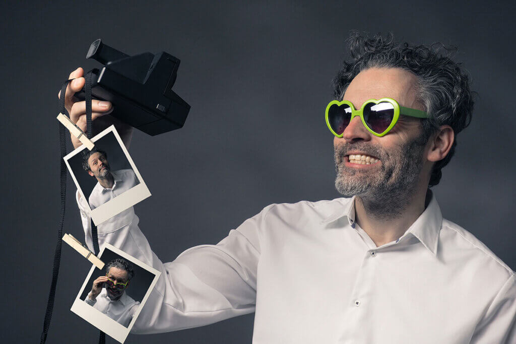 Mann macht Selfies mit Sofortbildkamera