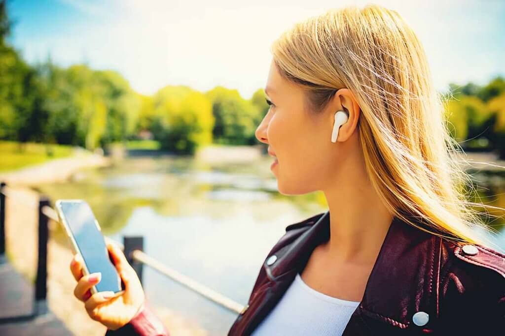 frau hoert kabellos musik vom smartphone mit ear buds