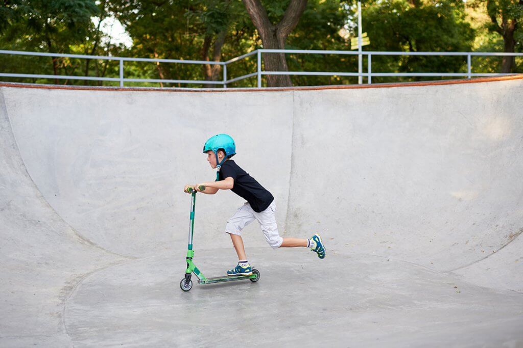 Kind faehrt mit Scooter im Skatepark