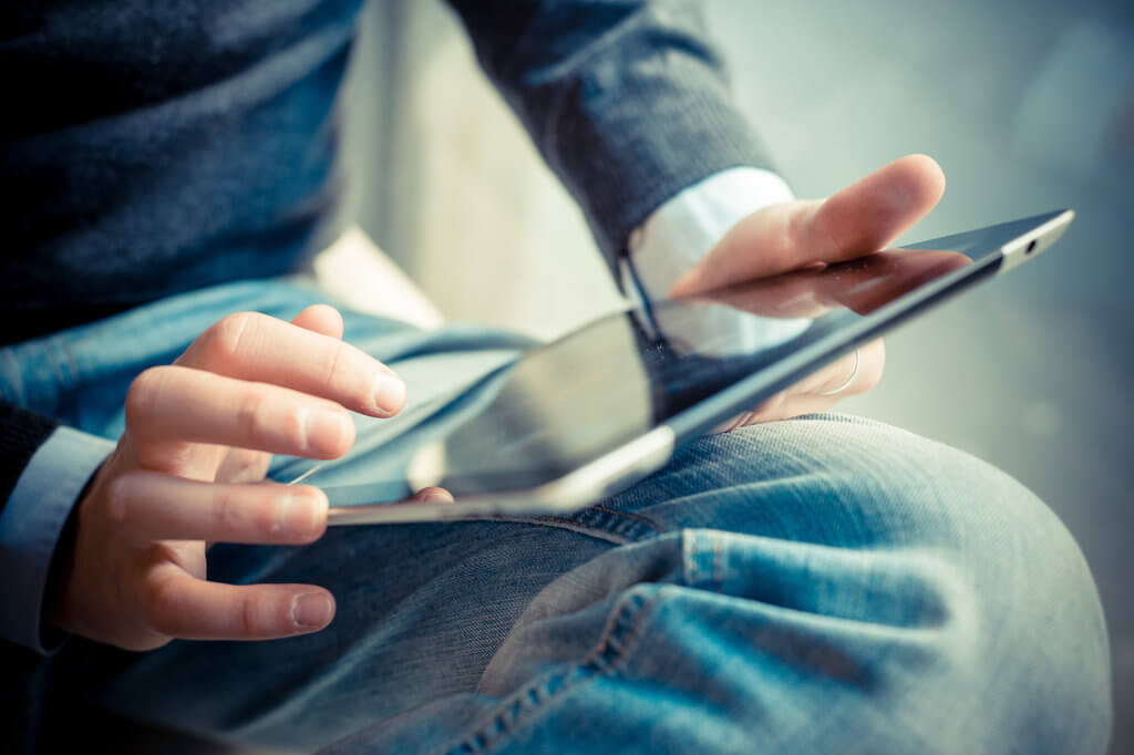 Mann arbeitet mit Tablet auf dem Schoss