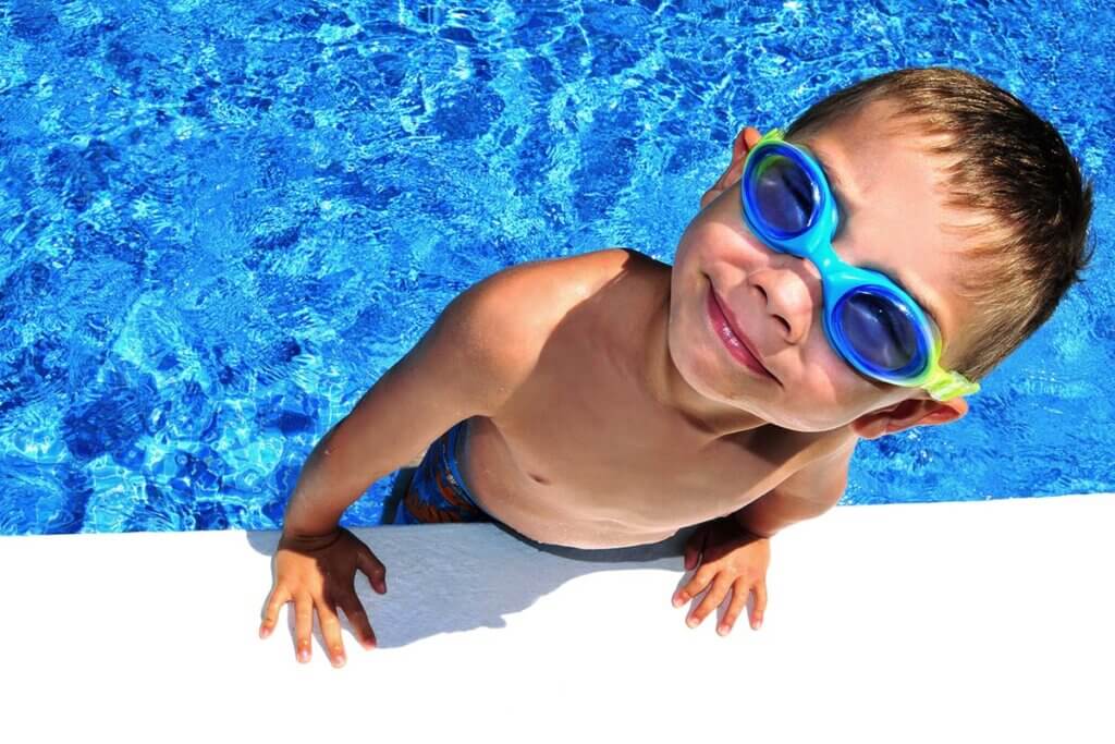 Kind mit Schwimmbrille steigt aus Pool