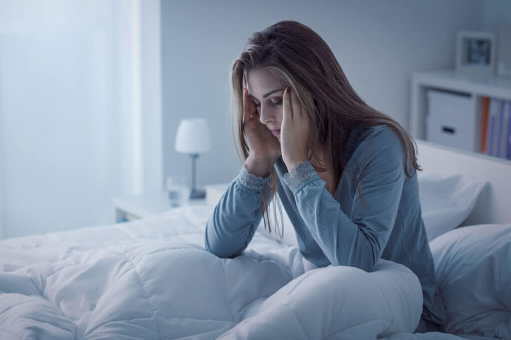 schalflose frau sitzt im bett. haelt sich die schlaefen