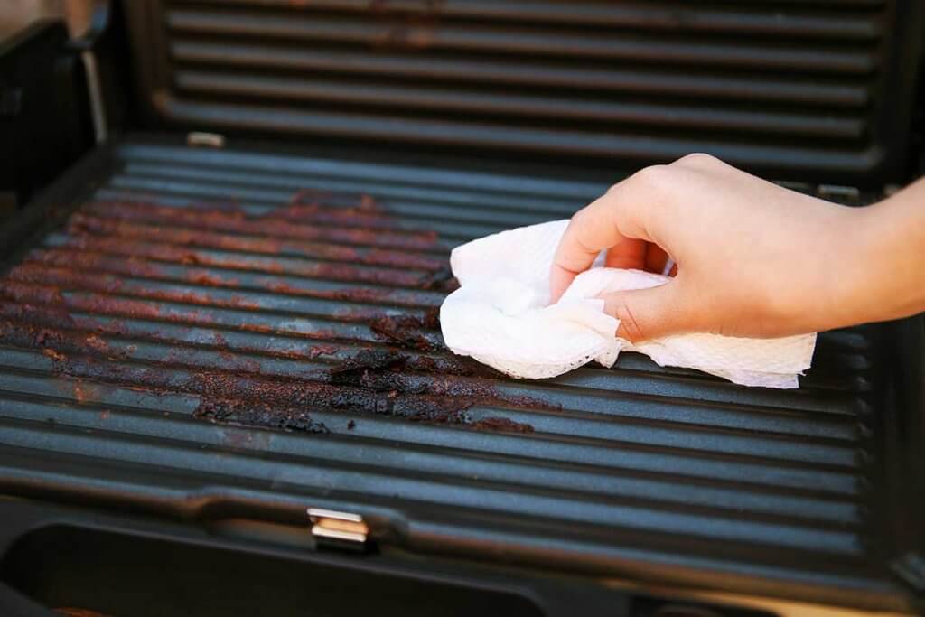 ein dreckiger Elektro-Grill wird gereinigt