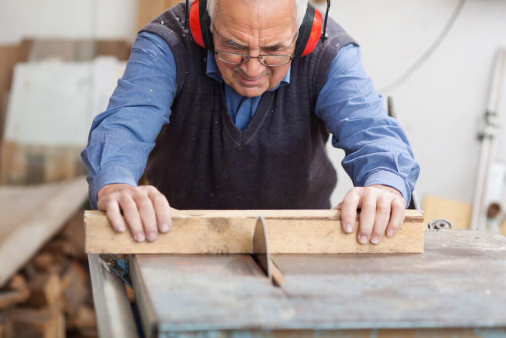 Mann sägt Holz mit Tischkreissäge