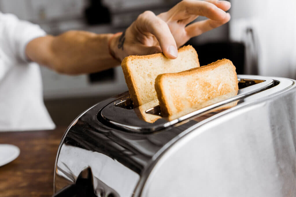 Mann nimmt sich Toast aus Schlitztoaster