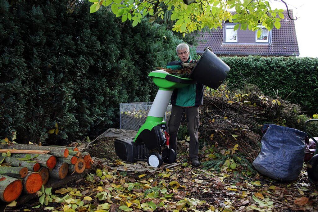 Mann häckselt im Garten