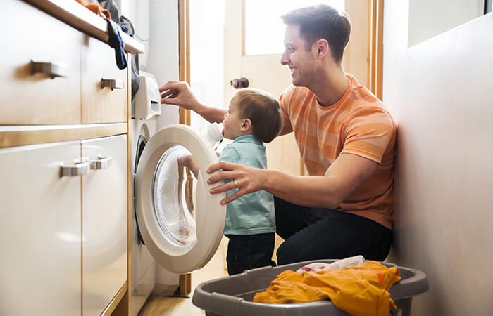 Vater mit Kind bedienen Waschmaschinen