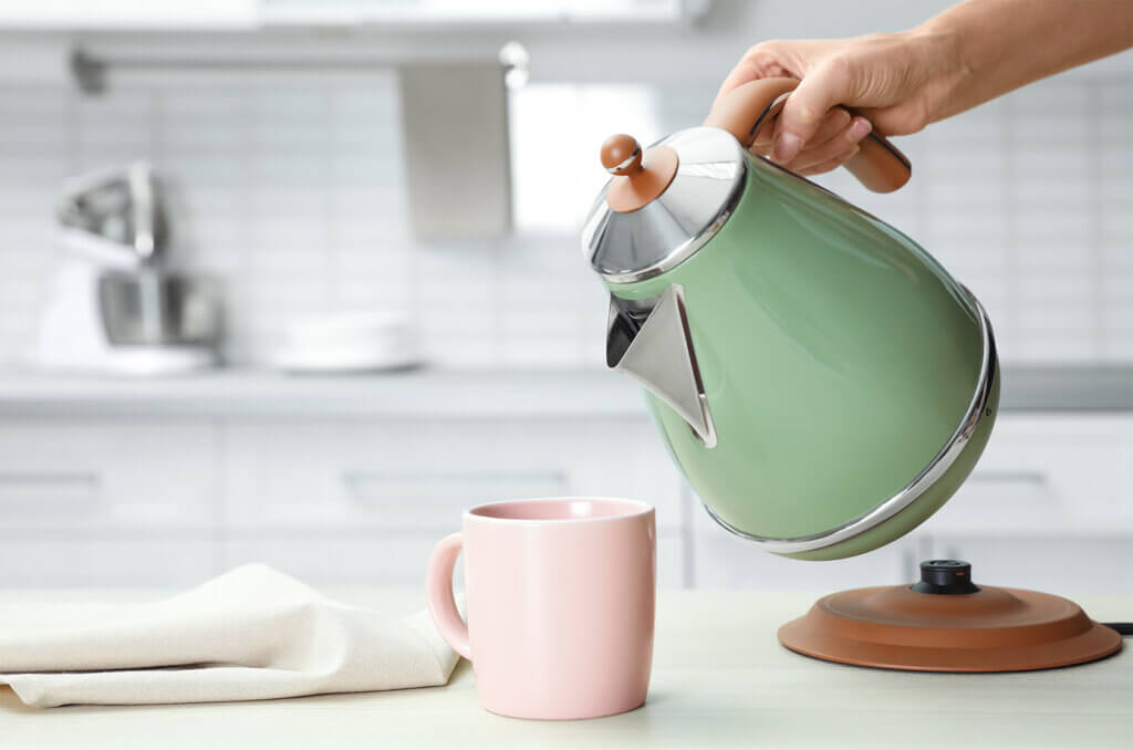 Frau gießt heißes Wasser in eine Tasse