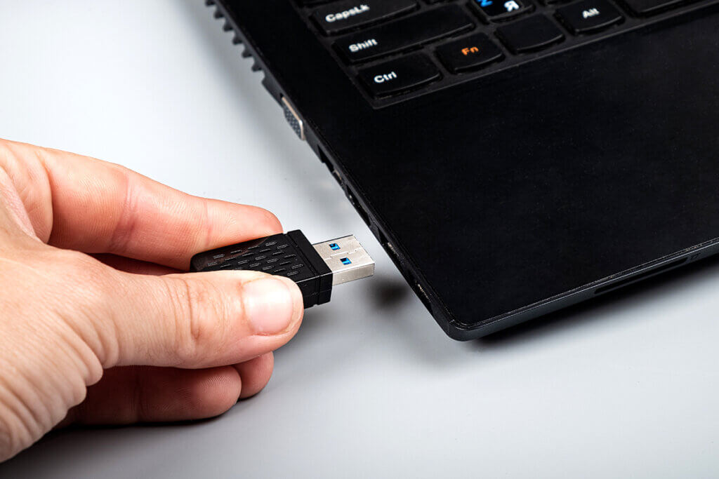 Person steckt WLAN-Stick in USB-Slot am Laptop