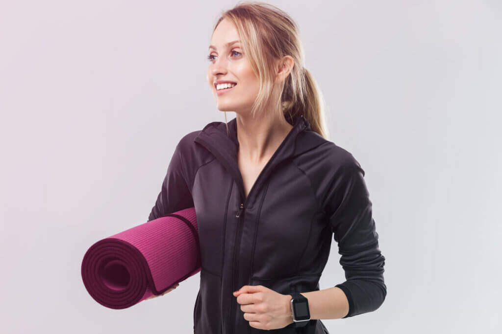 Frau mit Yogamatte unterm Arm