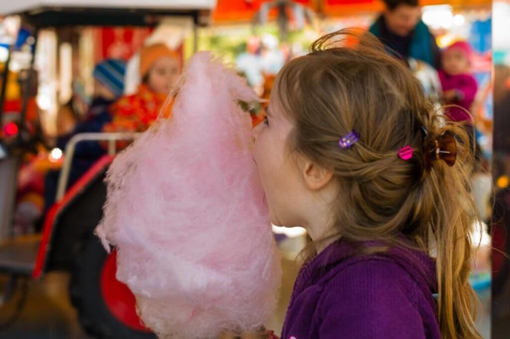 zuckerwattemaschinen-kind isst zuckerwatte auf jahrmarkt